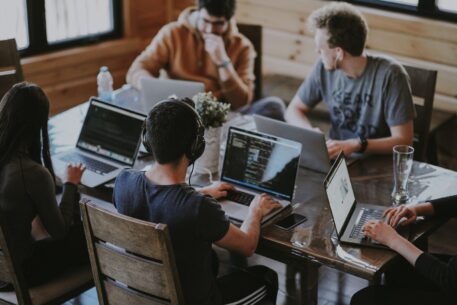 group of co-workers on laptops at meeting table